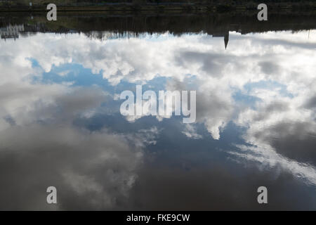 Reflections of the silhouettes of buildings and fluffy white clouds from the Waterside area of Derry on the River Foyle Derry Stock Photo