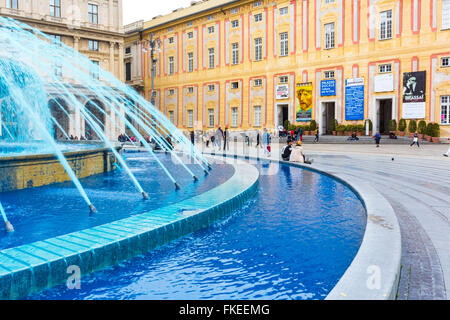 Fountain with blue water (colored to celebrate the boat show) in Piazza De Ferrari and Palazzo Ducale in the background Genoa Stock Photo