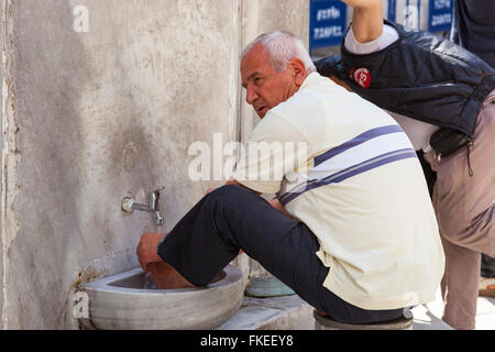 Muslim man washing his feet at the New Mosque, Eminonu Yeni Camii, Eminonu, Istanbul, Turkey Stock Photo