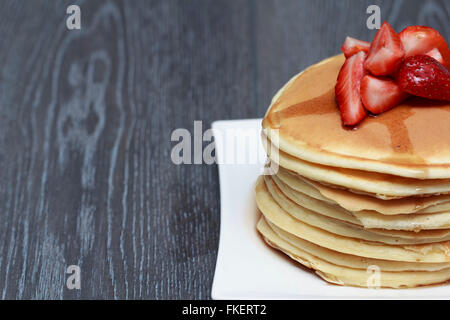 Stack of pancakes with strawberry on dark wooden background Stock Photo