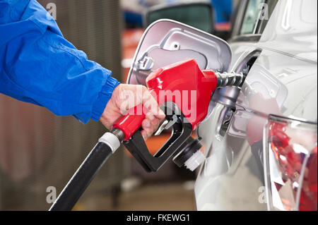 Woman Pumping Gasoline Into Silver Car With Red Fuel Nozzle Stock Photo