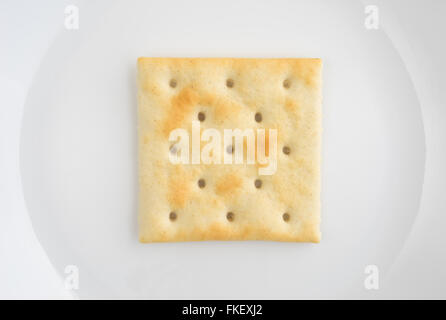 A very close view of an unsalted saltine cracker on an off white plate. Stock Photo