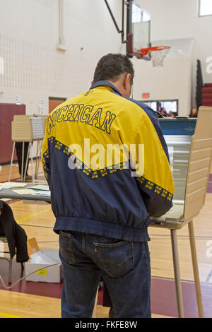Detroit, Michigan, USA. 8th March, 2016. A man wearing a Michigan jacket votes in Michigan's primary presidential election. Credit:  Jim West/Alamy Live News Stock Photo