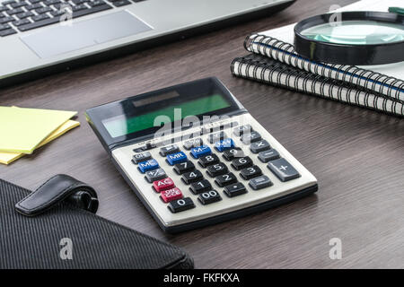 laptop, notebook, Adhesive Note and Magnifier with Calculator on the desk Stock Photo