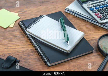 notebook, pen, Adhesive Note and Magnifier with Calculator on the desk Stock Photo