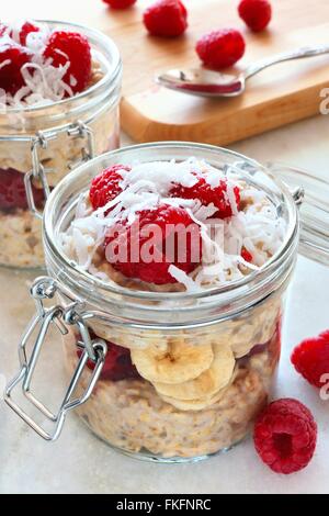 Healthy breakfast refrigerator oatmeal with fresh raspberries and shredded coconut in glass jars Stock Photo