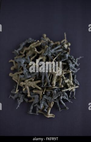 A pile of scattered fallen toy soldiers on a black background. Stock Photo