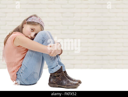 a pre-teen girl sad n is sitting on the floor Stock Photo