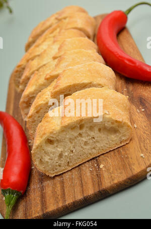 Baguette bread with two chilies on a kitchen table Stock Photo