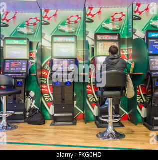 Woman using fixed odds betting terminal (FOBT fixed odds betting terminal) in Bookmakers in England, UK Stock Photo