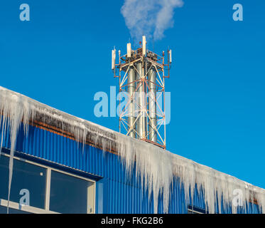 Large icicles hanging from the roof of the boiler house Stock Photo