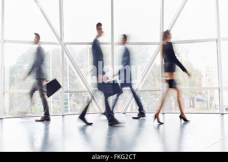 Group of business people going along the office corridor during working day