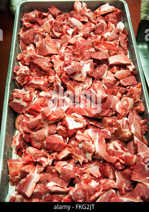 Close up view in long metal tray filled with dozens of raw, newly processed pork chop bits at meat processing plant Stock Photo