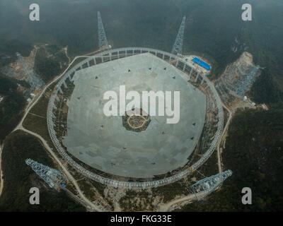 Pingtang. 9th Mar, 2016. Photo taken on March 9, 2016 shows an aerial view of the assembly site of the single-aperture spherical telescope 'FAST' in Pingtang County, southwest China's Guizhou Province. A total of 3,492 reflector panels, an equilateral triangle with a side length of 11 meters each, have been installed on the frame. When it is completed in 2016, the five hundred meter aperture spherical telescope (FAST) will be the world's largest, overtaking Puerto Rico's Arecibo Observatory, which is 300 meters in diameter. Credit:  Ou Dongqu/Xinhua/Alamy Live News Stock Photo