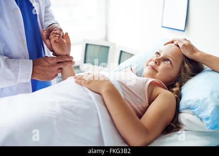 Little girl lying in bed while doctor examining her Stock Photo