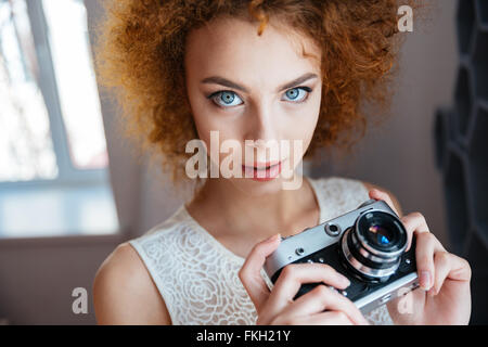 Portrait of beautiful redhead curly young woman photographer with vintage camera Stock Photo