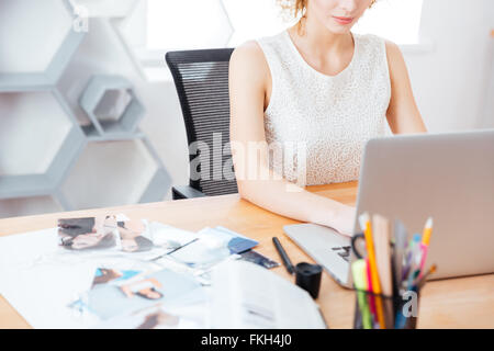 Pretty young woman photographer sitting and working with laptop in office Stock Photo