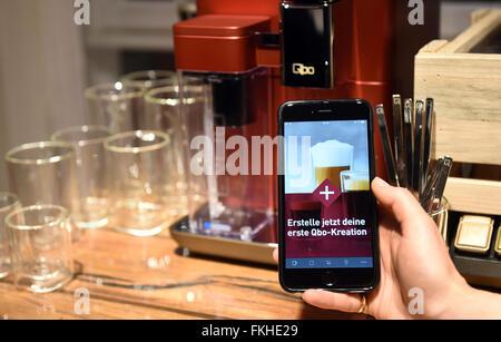 Berlin, Germany. 8th Mar, 2016. ILLUSTRATION - A man holds a smart phone in his hand which displays a new app that allows users to send individual coffee orders to a coffee machine of the Tchibo brand Qbo during an advertising presentation of a new type of coffee capsules in Berlin, Germany, 8 March 2016. Photo: Jens Kalaene/dpa/Alamy Live News Stock Photo