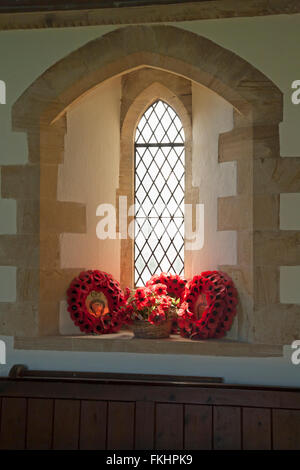 The Royal British Legion red poppy wreaths in window of St Mary's Church at Tyneham Village, Dorset UK in July - Saint Marys Church, St Mary Church Stock Photo