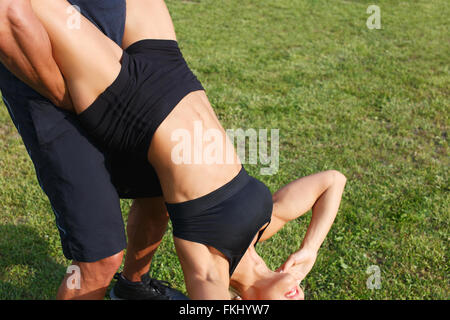 Young woman doing sit ups with personal trainer in nature, extreme workout, outdoors Stock Photo