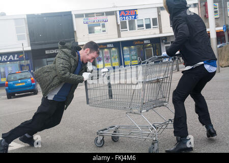 Newquay, Cornwall, UK. 9th March 2016. UK Weather. High winds of over 70 mph have caused widespread damage across Cornwall today, with thousands of homes without electricity and hundreds of trees down. In Newquay roofs were ripped off units at an industrial estate, and people were struggling to stand up in the strong winds. Seen here supermarket assistants wrestling to move trolleys to safety. Credit:  Simon Maycock/Alamy Live News Stock Photo