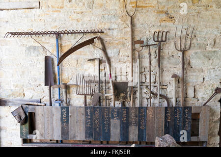 Selection of tools on wall of old buildings at Tyneham Farm, Dorset, UK in March Stock Photo