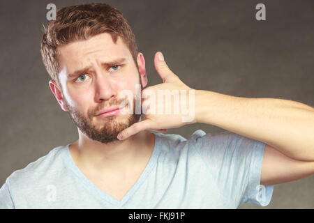 Young man guy with hand palm to ear showing call me gesture in studio on black. Stock Photo