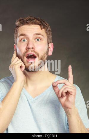 Portrait of surprised scared handsome man pointing at empty blank copy space. Young guy in studio on black. Advertisement. Stock Photo
