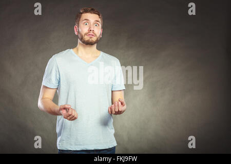 Portrait of scared afraid shocked handsome man in shirt. Young guy posing in studio on black. Stock Photo