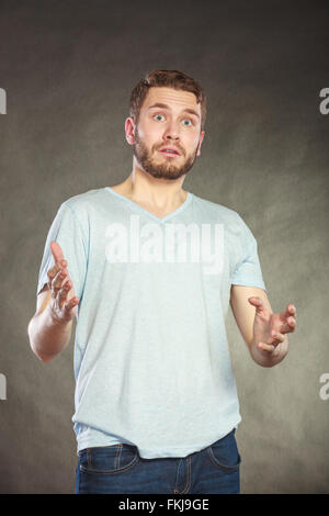 Portrait of shocked surprised amazed handsome man in shirt. Young guy posing in studio on black. Stock Photo