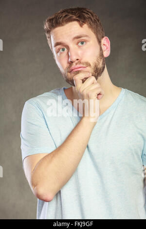 Portrait of pensive thoughtful handsome man in shirt. Young guy thinking in studio on black. Stock Photo