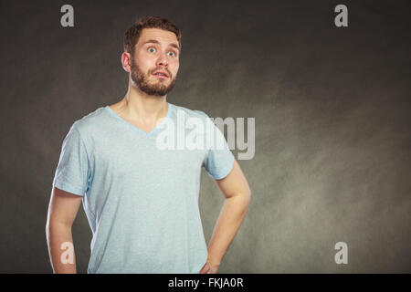 Portrait of scared afraid shocked handsome man in shirt. Young guy posing in studio on black. Stock Photo