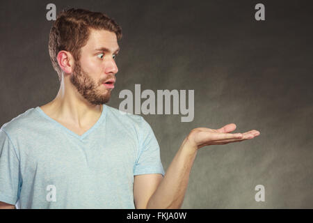 Portrait of handsome man with open empty hand palm for copy space. Young guy in studio on black. Advertisement. Instagram filter Stock Photo