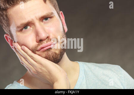 Man suffering from toothache tooth pain. Young guy in studio on black. Stock Photo