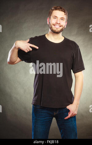 Portrait of happy handsome fashionable casual man in black blank shirt with empty copy space pointing at himself. Young guy. Stock Photo