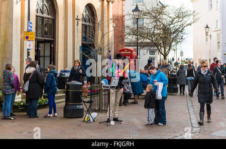 A street balloon seller makes animal shapes from balloons for a child  in Sidmouth town centre. Stock Photo