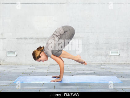 woman making yoga in crane pose on mat Stock Photo