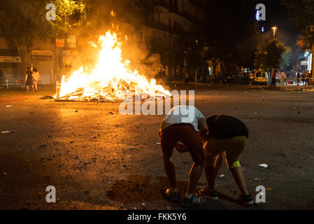 People around a campfire at night to celebrate the festivity of Sant Joan on a street in Barcelona, Catalonia, Spain Stock Photo