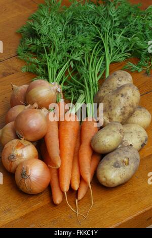 Crop of fresh organic potatoes, carrots and onions on a wooden background Stock Photo
