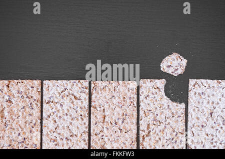 Top view of whole grain crispy crackers with seeds on a black wooden table. Stock Photo
