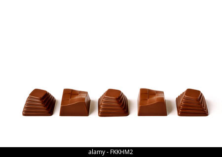 White, dark and milk chocolate pralines in a ceramic spoon on a purple textured background. Stock Photo