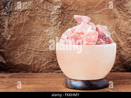 Turned off Himalayan pink salt lamp carved as a bowl on a wooden table. Stock Photo