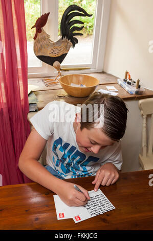 An 11 year old boy writes a postcard from his family holiday in the Uk Stock Photo