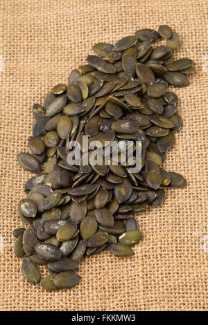 Heap of unshelled pumpkin seeds on burlap background Stock Photo