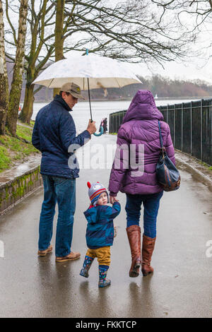 A young family going to feed the ducks on a rainy, wet day at Roundhay Park, Leeds, Yorkshire UK Stock Photo