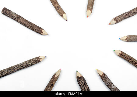 Above studio shot of pencil crayons set in bark arranged in circular pattern on white Stock Photo
