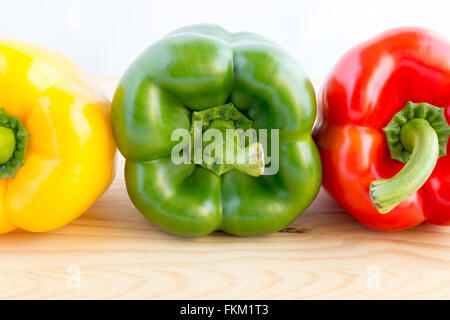 Three bell peppers in a row in different colours, yellow, green and red Stock Photo