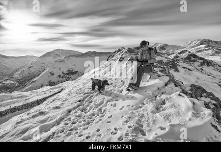 A hiker resting on the mountains tops with their dog in the UK. Grain and colour styling applied Stock Photo