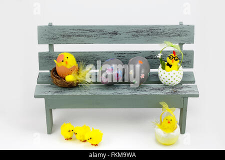 Composition with chick figurines and easter eggs, placed in a bench Stock Photo