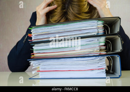 tired businesswoman stressed with pile of folders Stock Photo